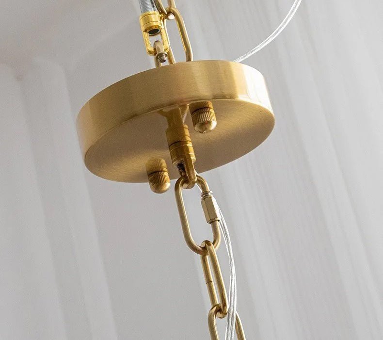 The brass ceiling plate and chain that carry the fitting, seen close