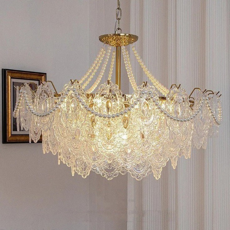 The lit fitting in a pale room beside framed pictures and a sheer curtain