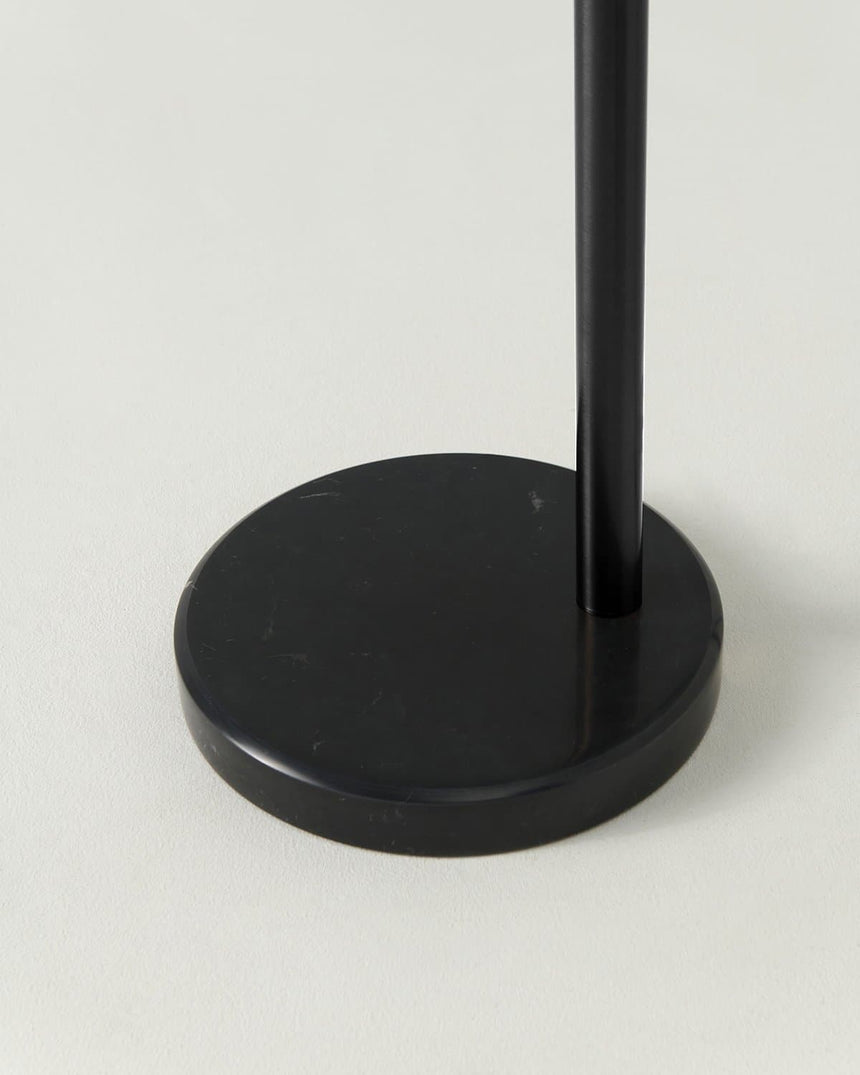 The black pole in the same round base, seen from the side at floor level