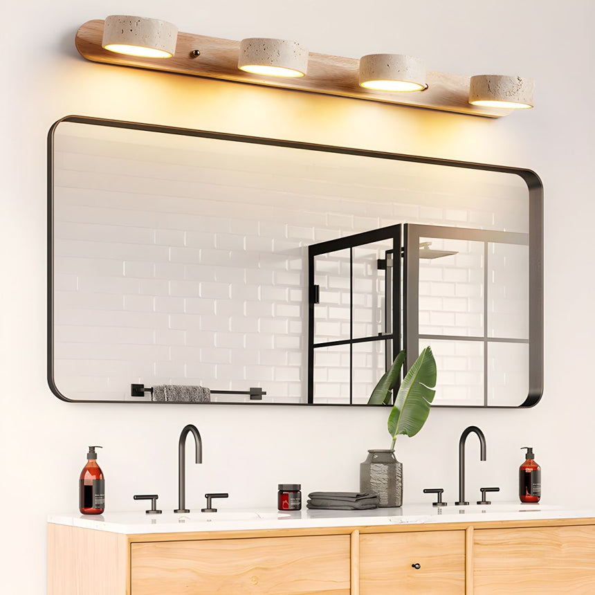 Four discs lit above a black framed mirror over a wood vanity with two taps
