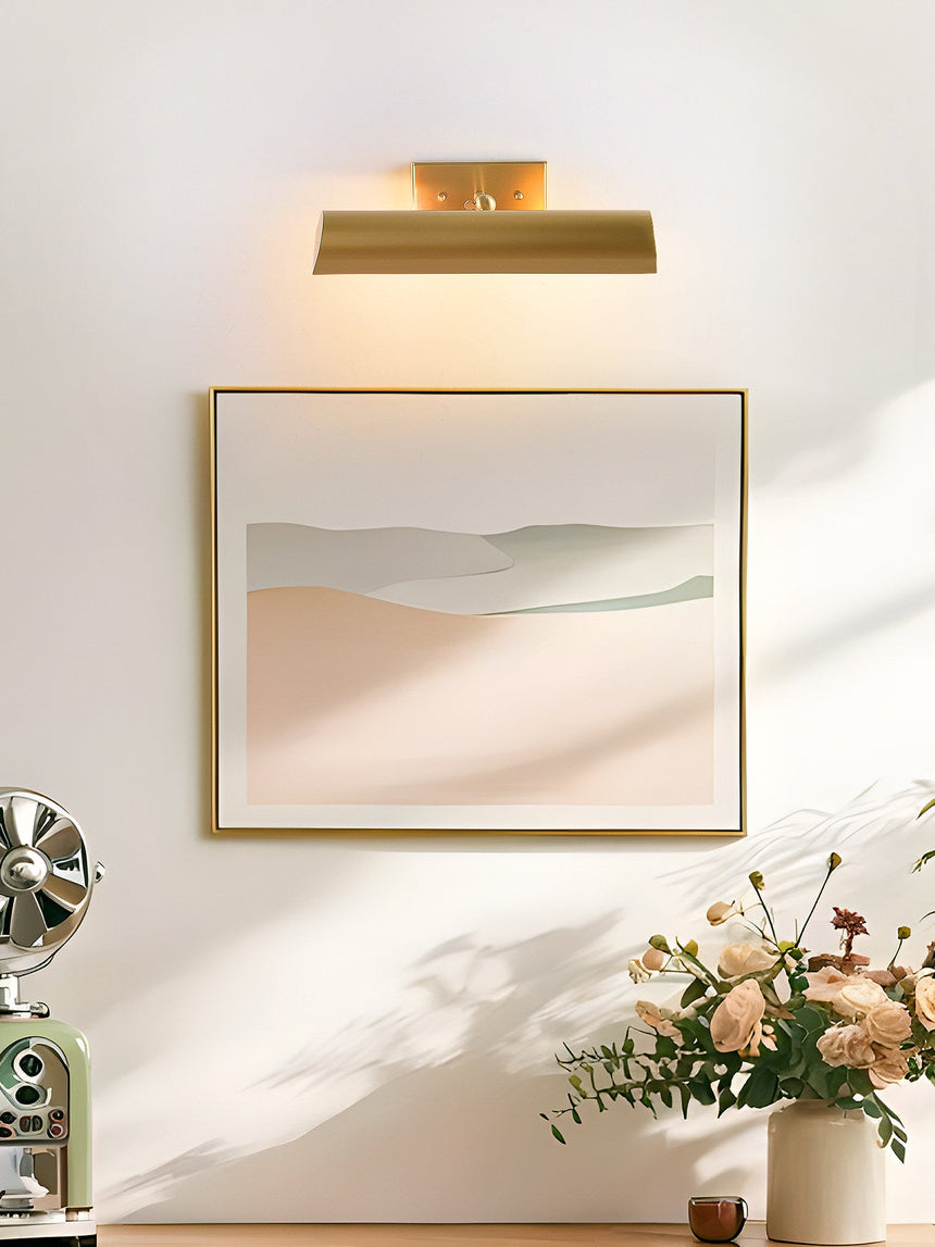 Brass shade lit over a framed print with flowers on the console below