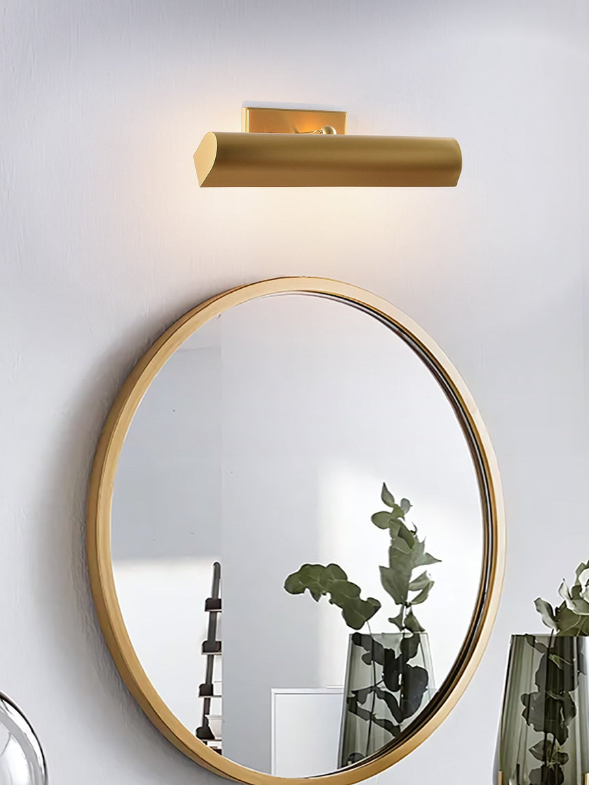 Brass shade lit above an oval mirror with glass jars on the counter