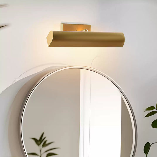 Brass shade lit above a round mirror with a plant beside the basin