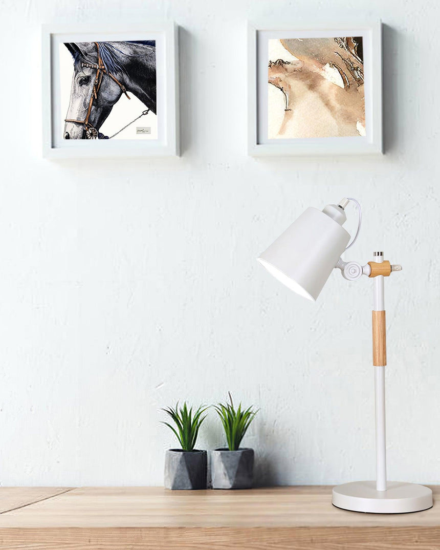 Adjustable desk lamp unlit on a white shelf below two framed photos