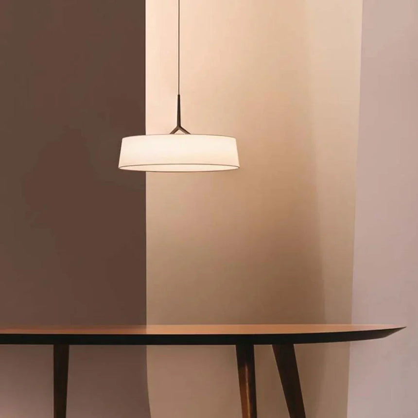 Flat drum shade above a table in a dark room