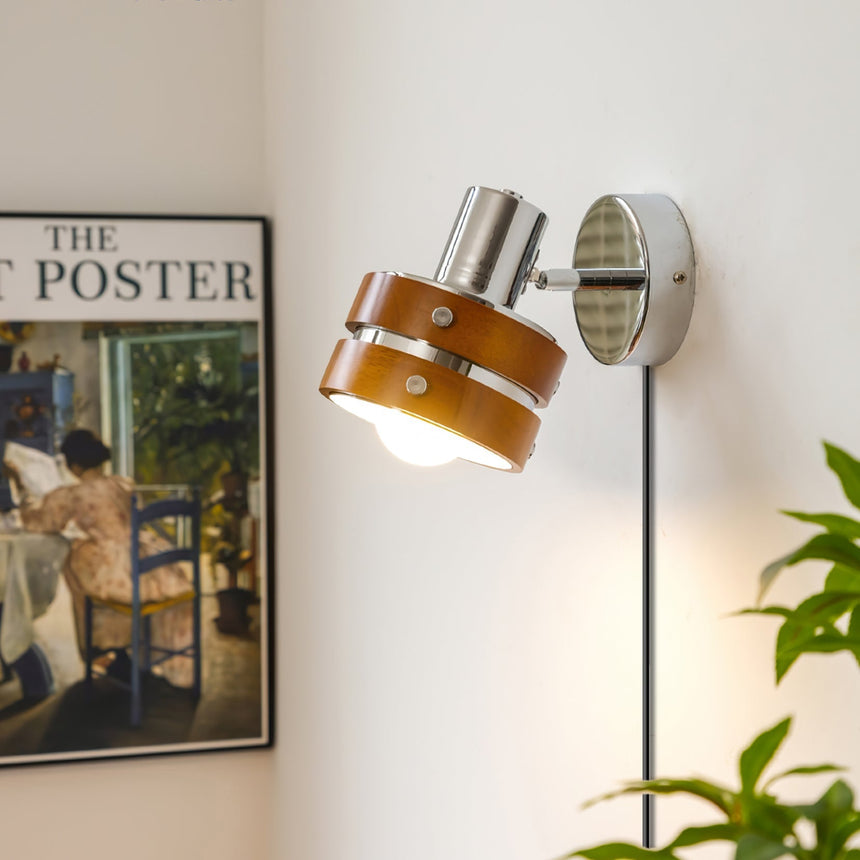 Sconce lit on a wall beside a framed print and a green plant
