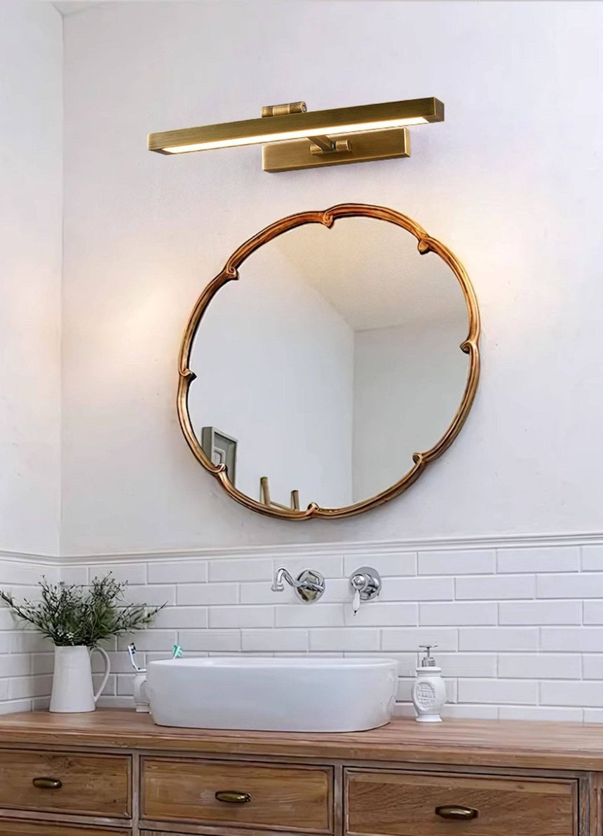 Brass bar above a round mirror over a basin set on a wood vanity