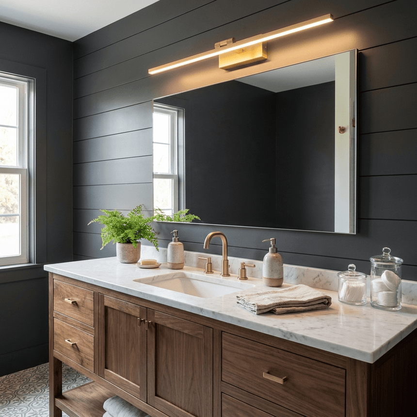 Brass bar lit above a mirror on a dark shiplap wall over a wood vanity with a fern