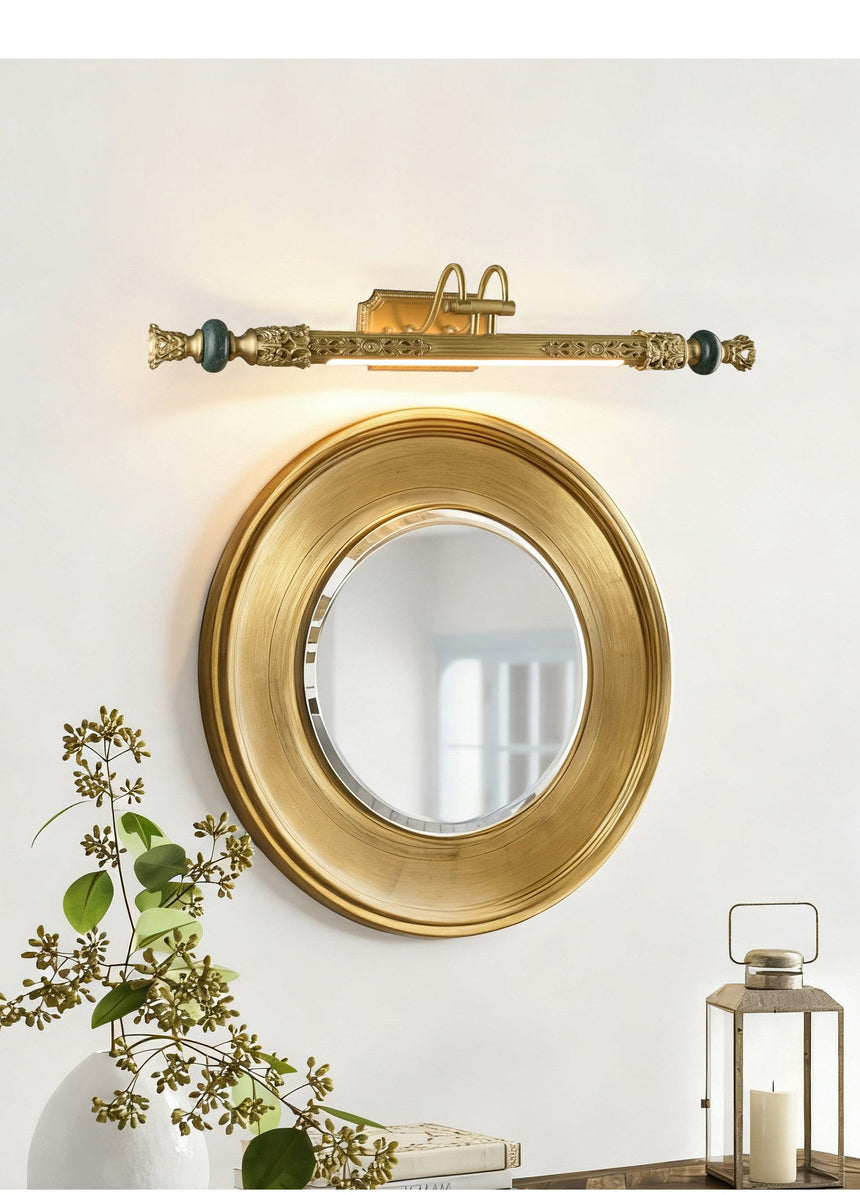 Ornate brass bar above a round gilt mirror beside a lantern and foliage