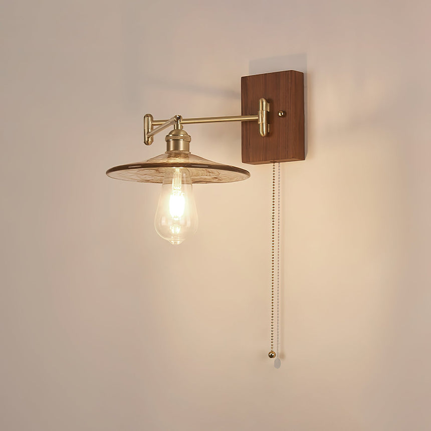 Clear glass disc lit with a visible filament lamp under a brass arm