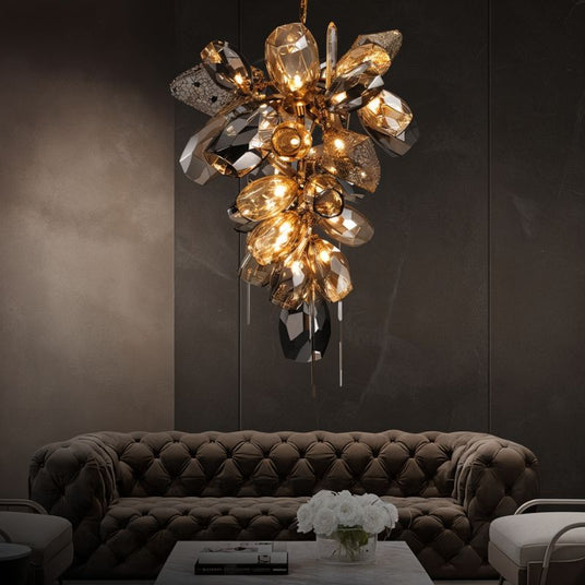 The tall cascade lit above a tufted sofa, a coffee table and white flowers