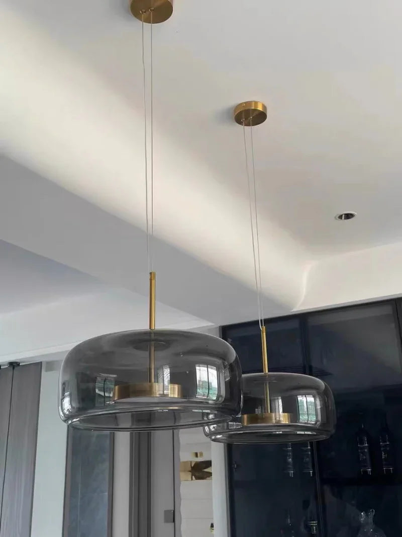 Two smoke gray bell pendants lit side by side above a counter