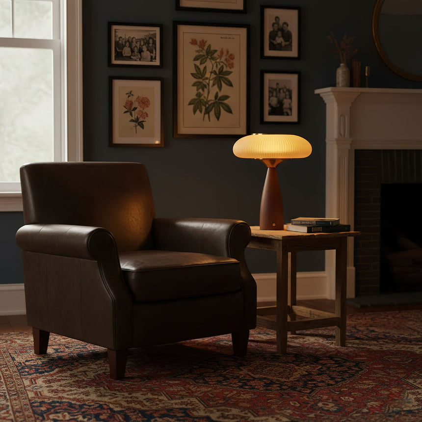 Amber glass table lamp lit on a side table beside a leather armchair