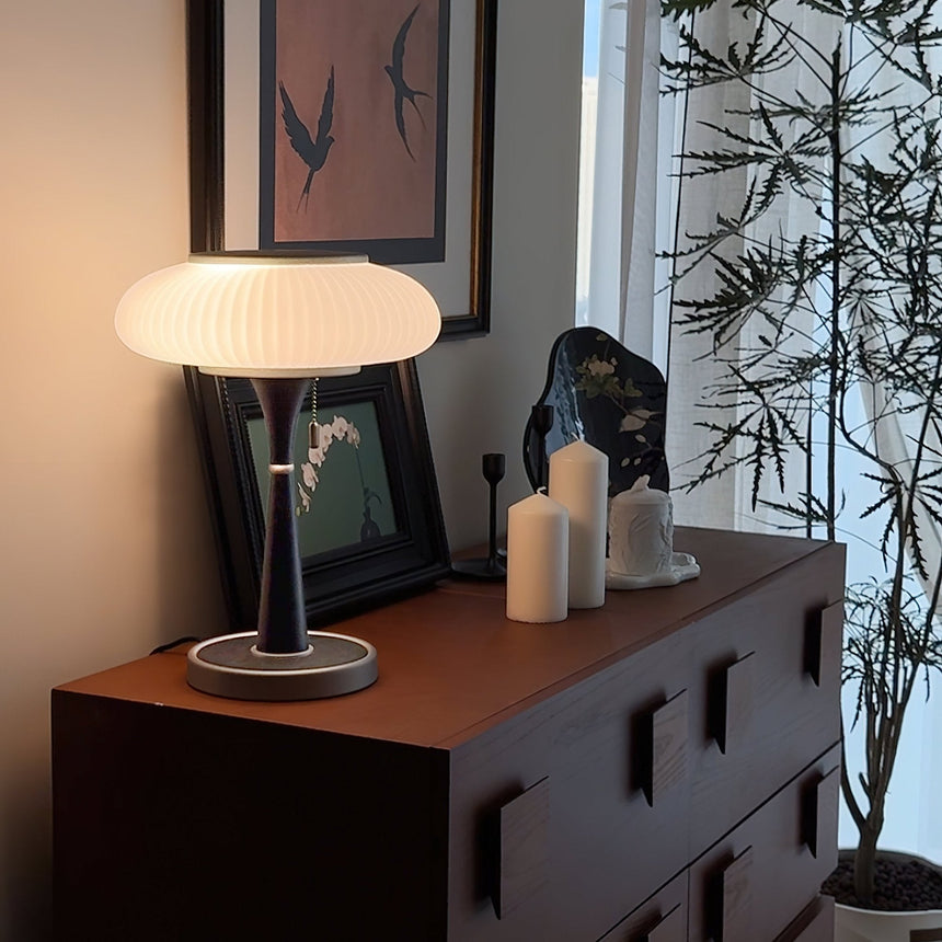 The white glass version lit on a dark cabinet beside candles