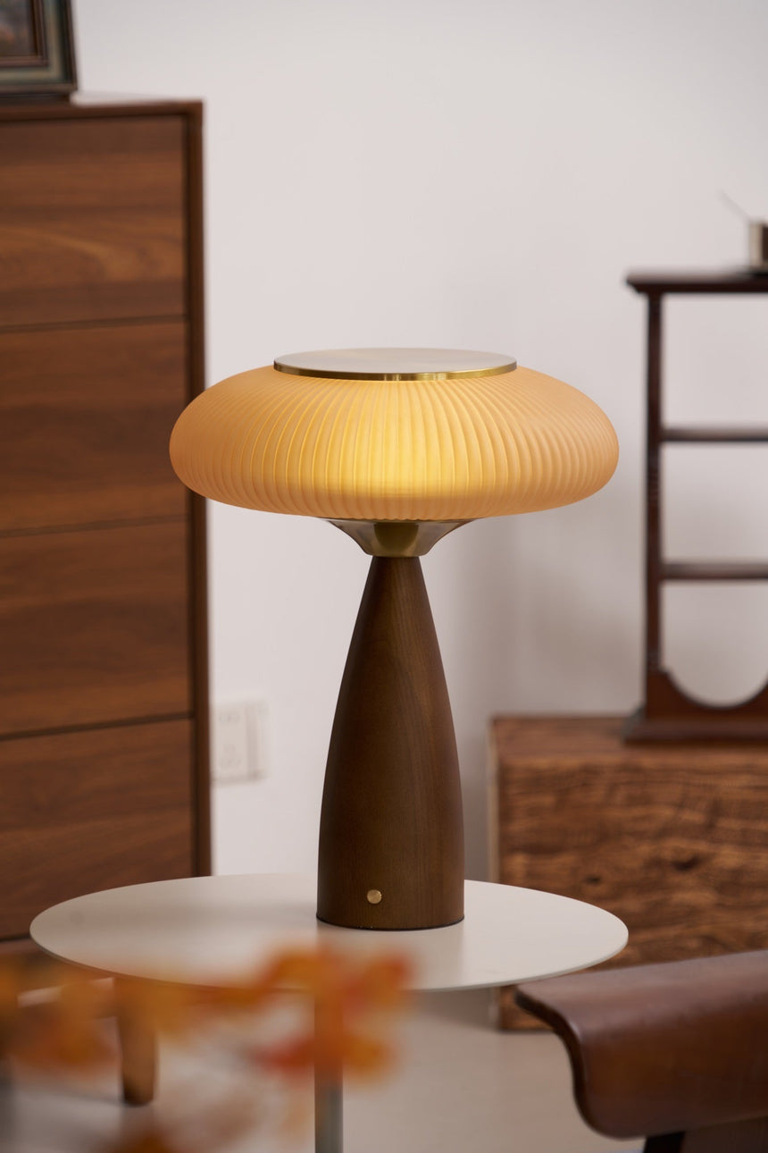 Amber glass table lamp lit on a white table beside a walnut dresser
