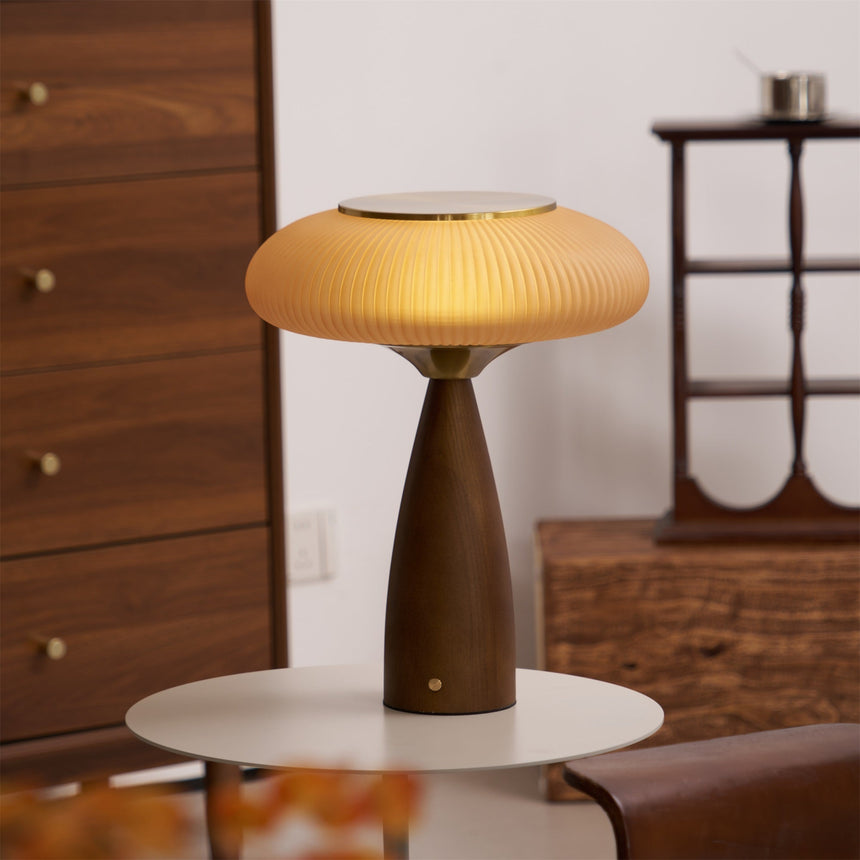 Amber glass table lamp lit on a round side table beside a dresser