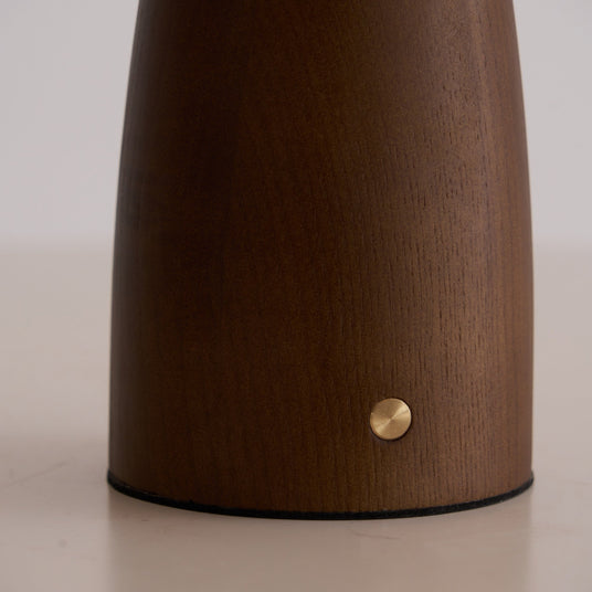 Close view of the brass touch button on the side of the walnut cone