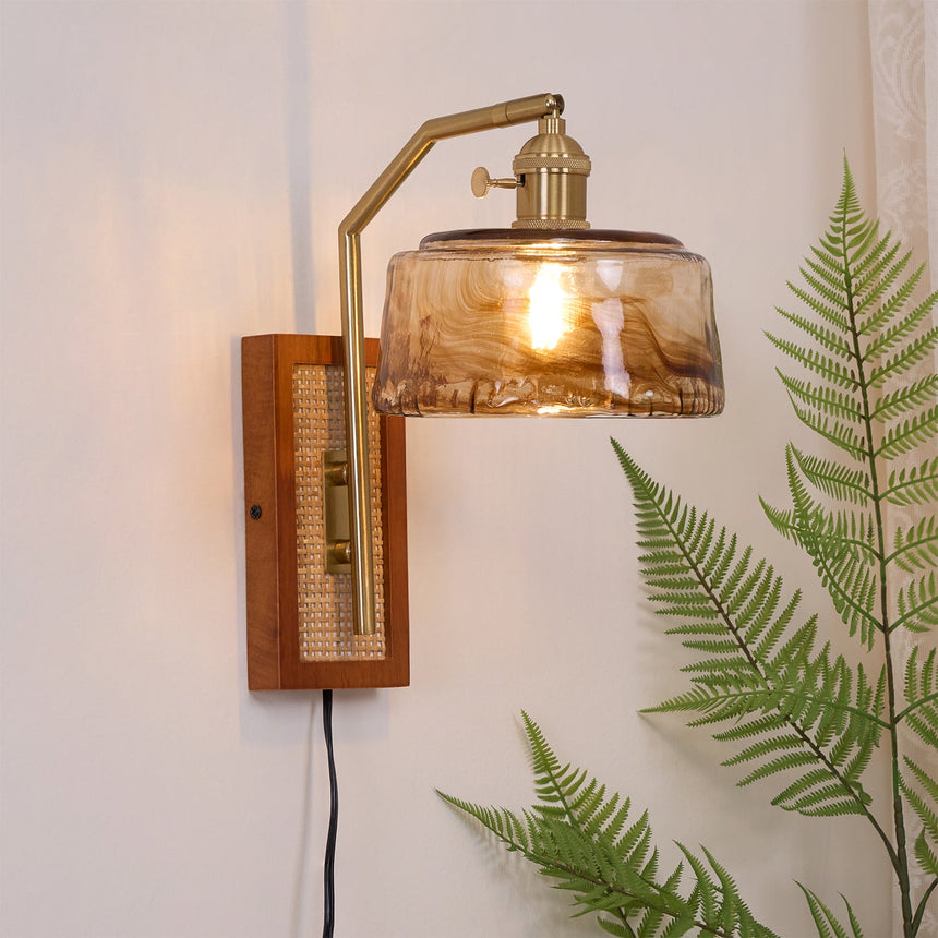 The amber drum shade lit beside a fern, the walnut plate and cord below