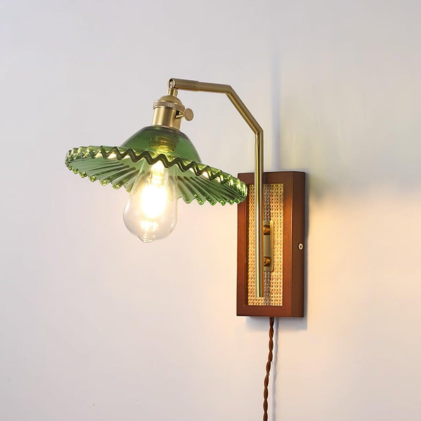 The green ruffled glass shade lit on a plain wall
