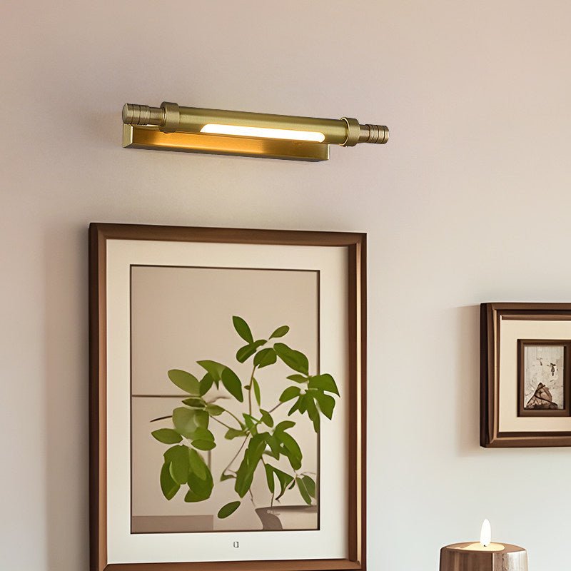 Brass tube lit over a framed botanical print beside a lit candle