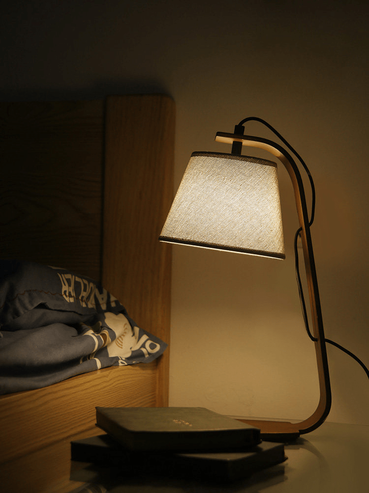 Arc lamp lit at night on a bedside surface beside folded clothes