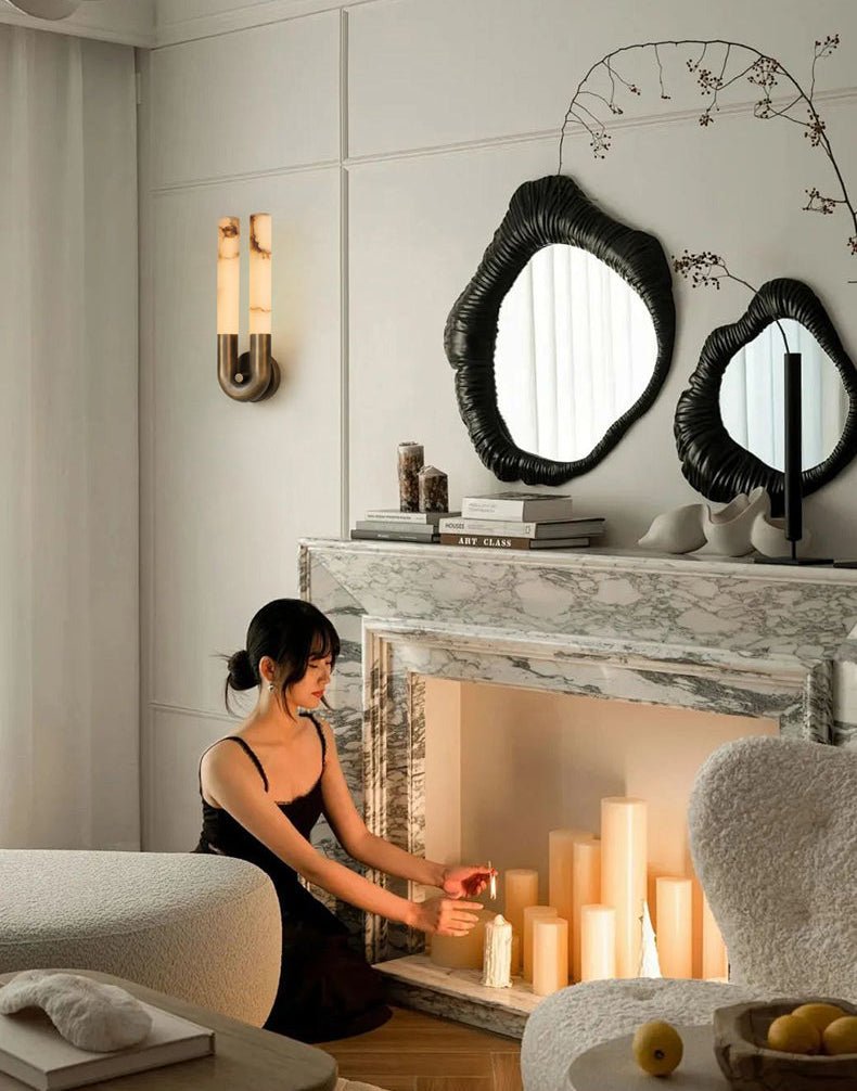 The sconce lit beside a stone mantel with candles and round mirrors