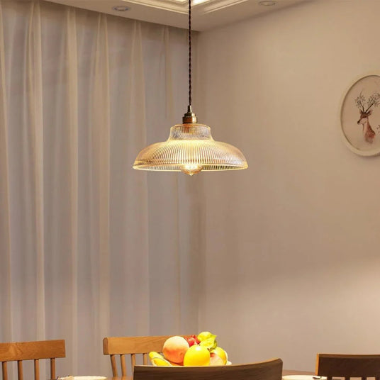 Amber shade above a wooden dining table set with fruit and spindle chairs