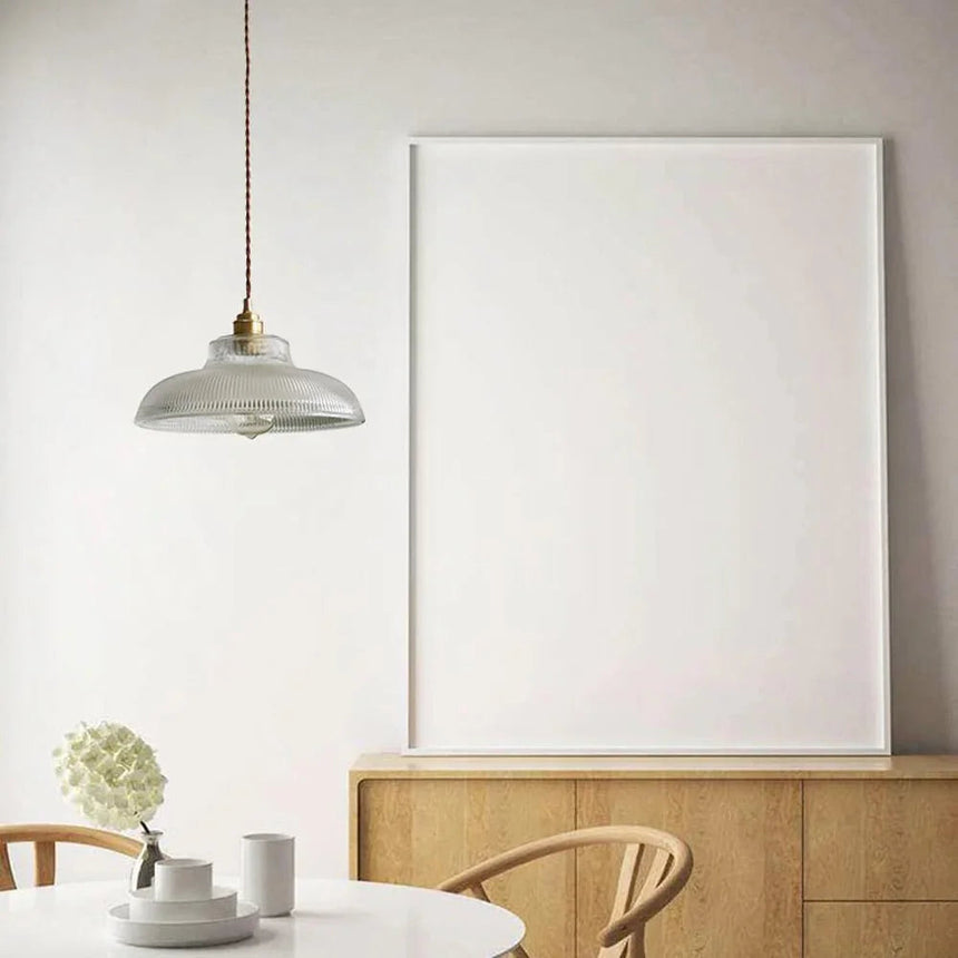Clear shade above a wooden sideboard with a leaning picture frame behind
