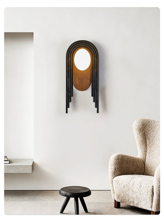 The arch lamp on a white wall above a wool armchair and a low black stool