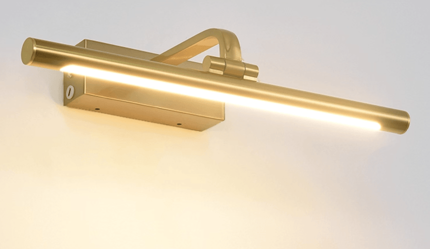 The tube lit warm, the gold arm and the wall plate seen from a low angle