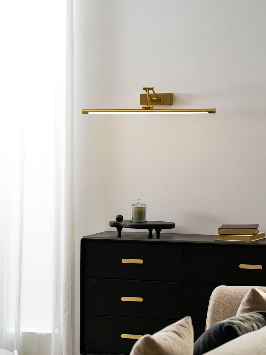 Lit on a pale wall above a sofa and a long curtain, the beam falling downward