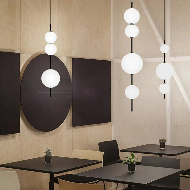 Spheres hung above cafe tables beside a round wall mirror and a plant