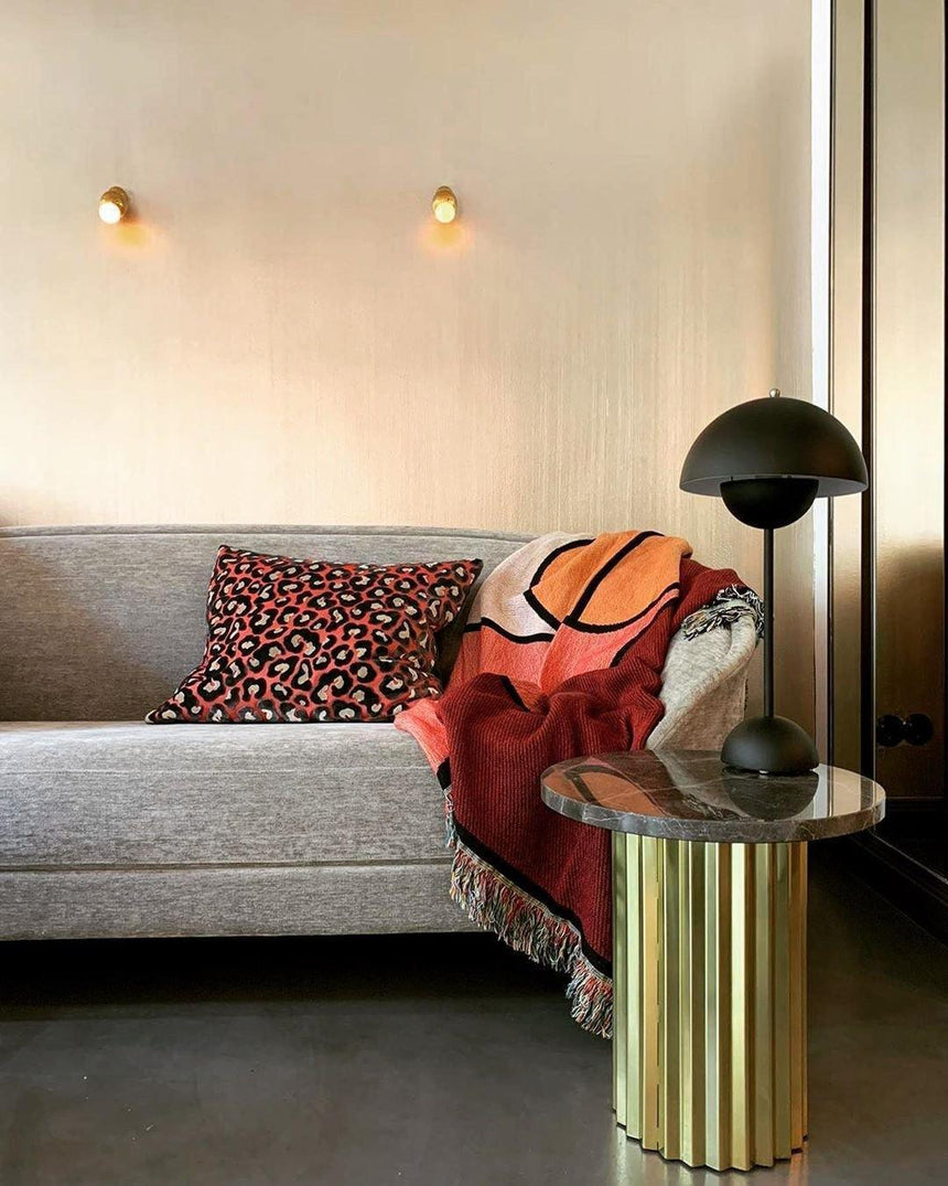 Two ball lights lit above a gray sofa beside a gold side table