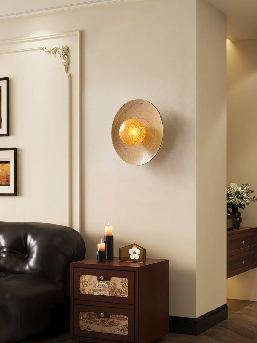 Sconce lit in a living room above a dresser with candles and framed prints