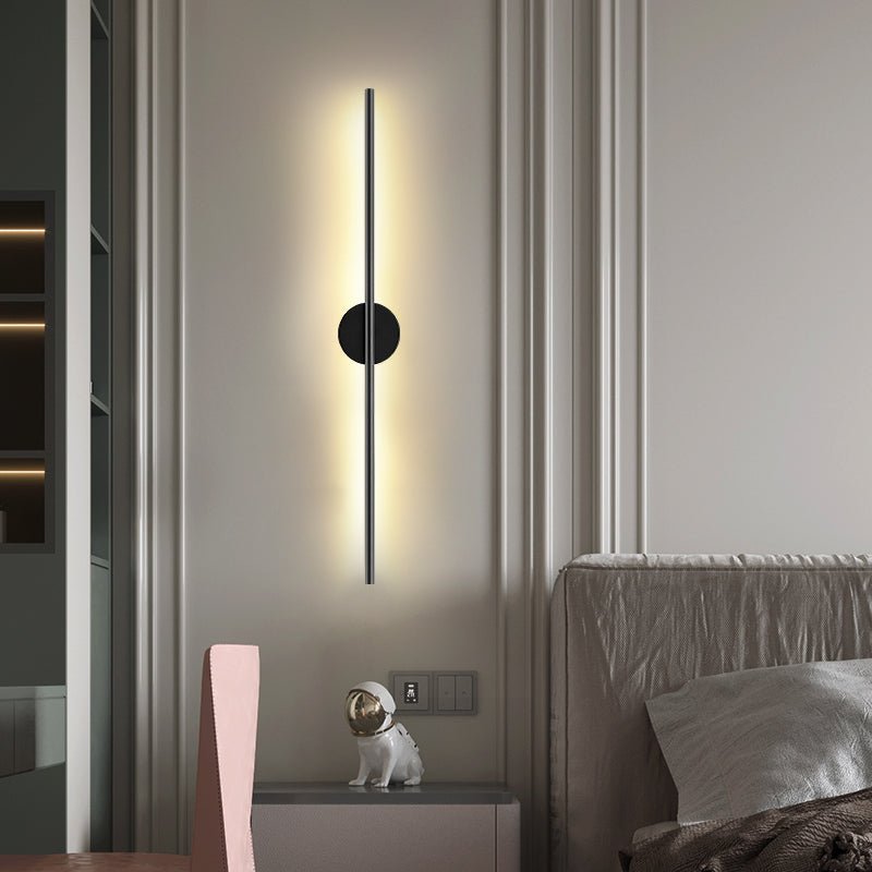 Lit beside an open doorway in a bedroom, a nightstand and bed just visible