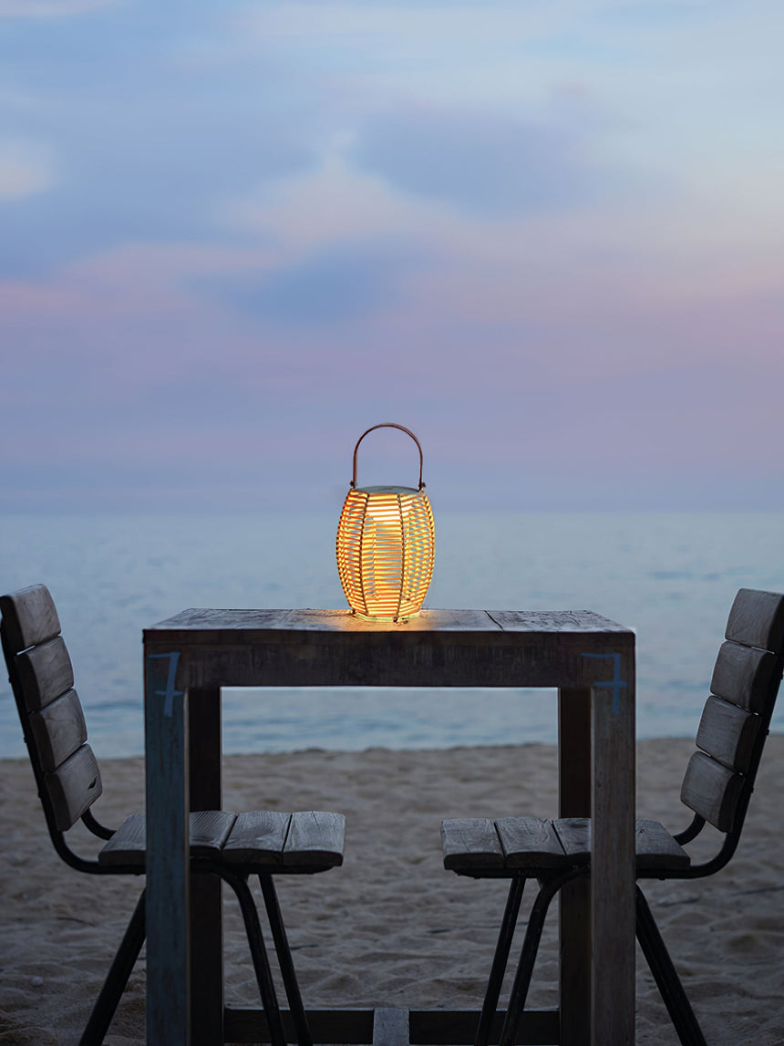 One lit on a high table with two chairs facing the sea at dusk