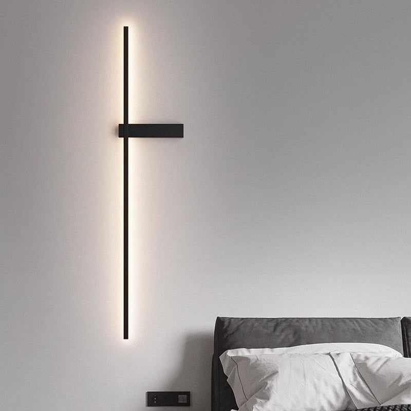 Lit above a bed with white pillows, the rod running down beside the headboard