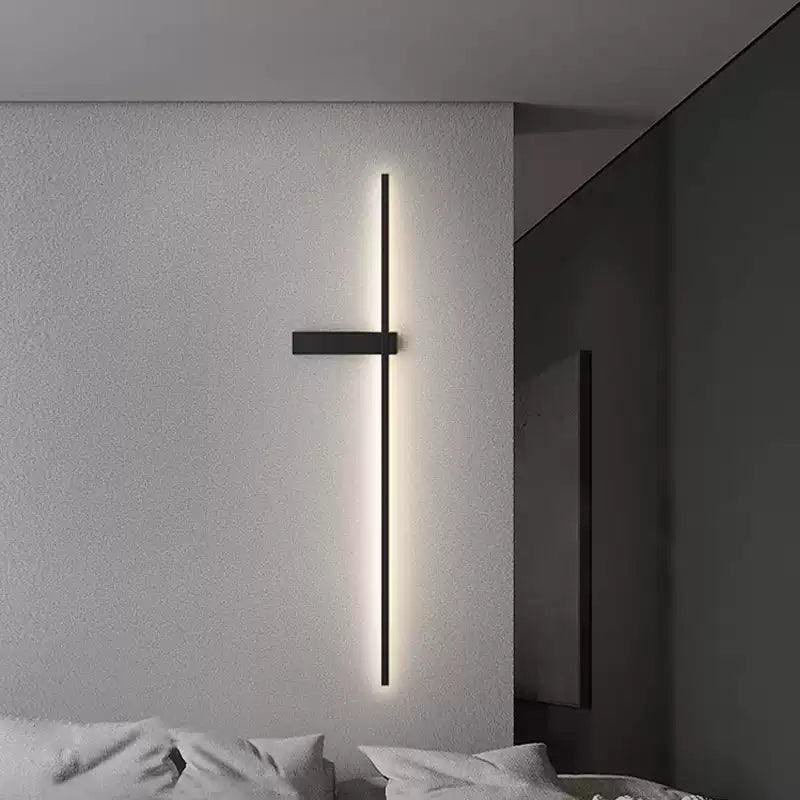 Lit on a bedroom wall beside a bed with pale bedding and a dark partition