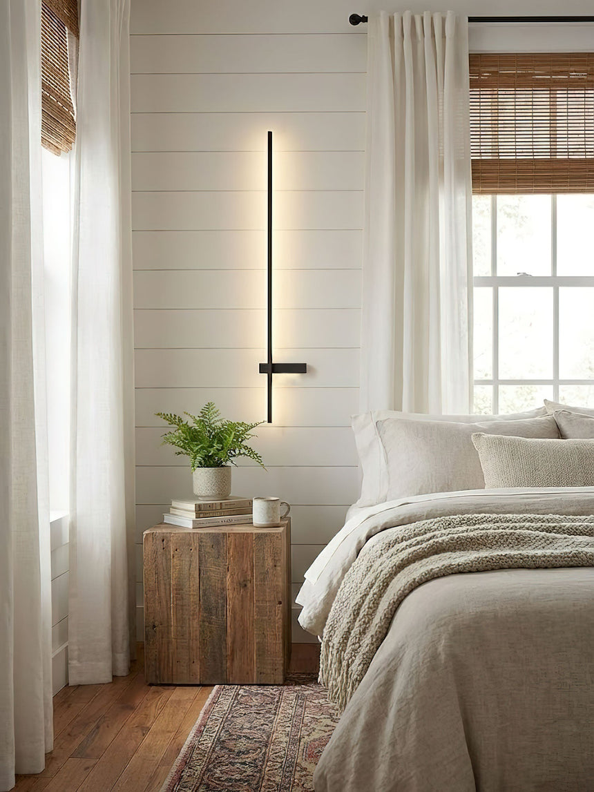 Lit in a bedroom beside a window, a timber nightstand and a small plant