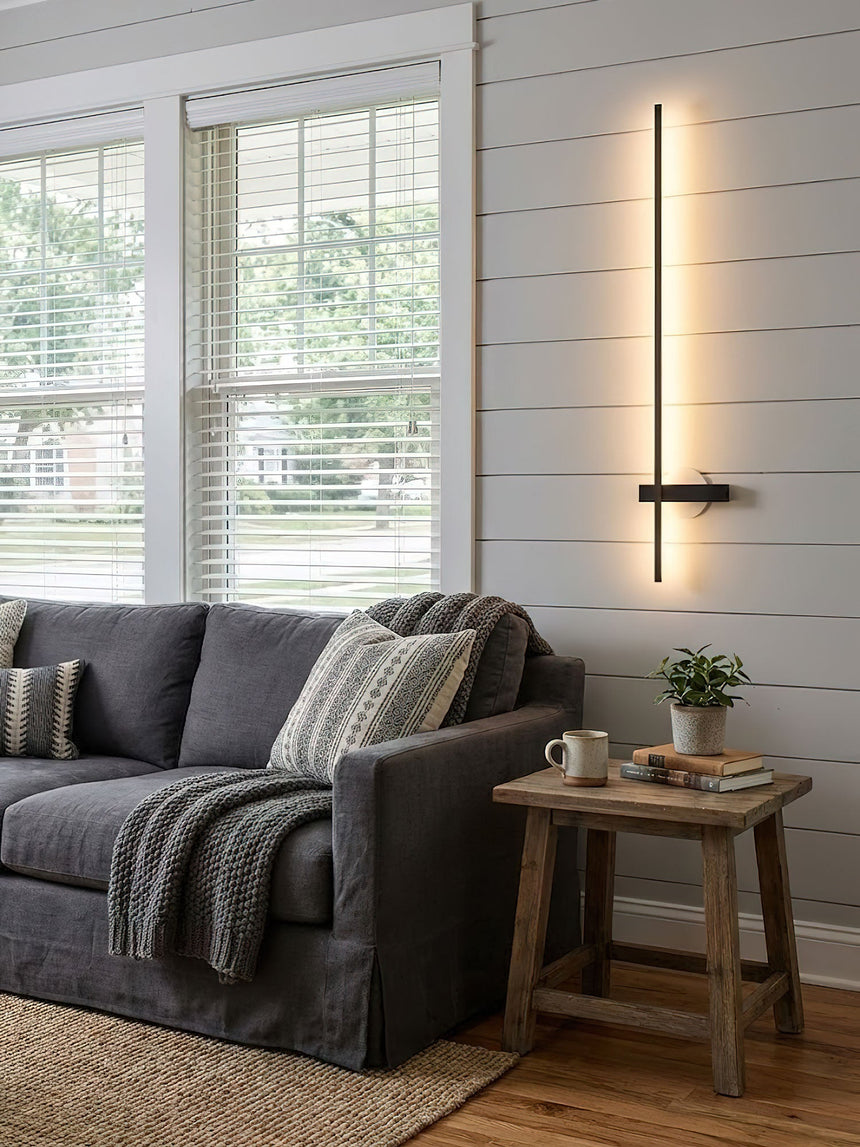 Lit above a gray sofa beside a wood side table with a mug and a book on it