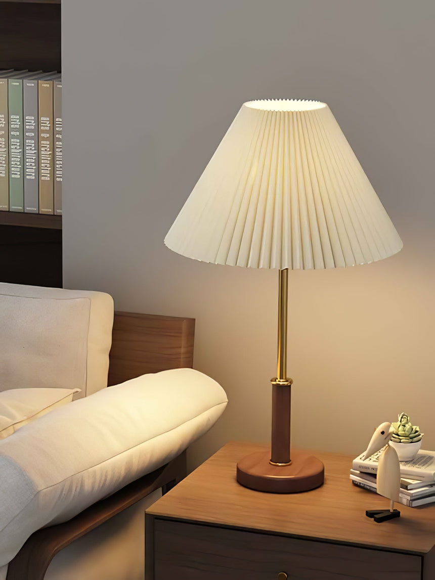Pleated shade lamp lit on a side table beside a pale armchair