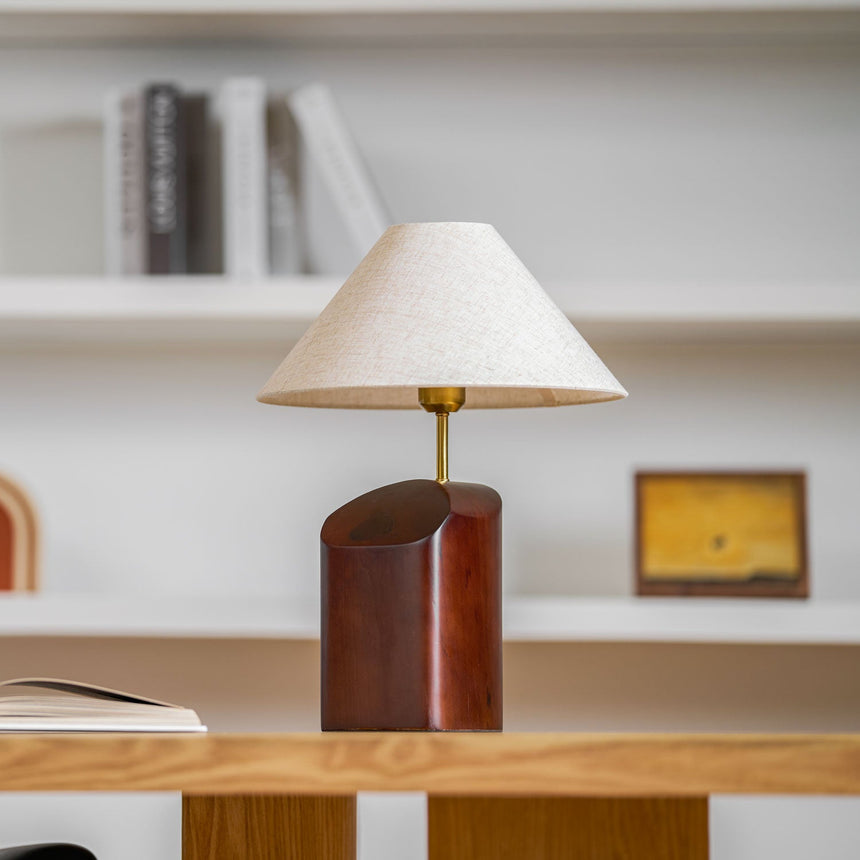 Bedroom table lamp lit on a desk in front of a bookshelf