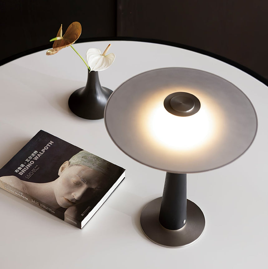 The wide disc of the bedroom table lamp seen lit from above