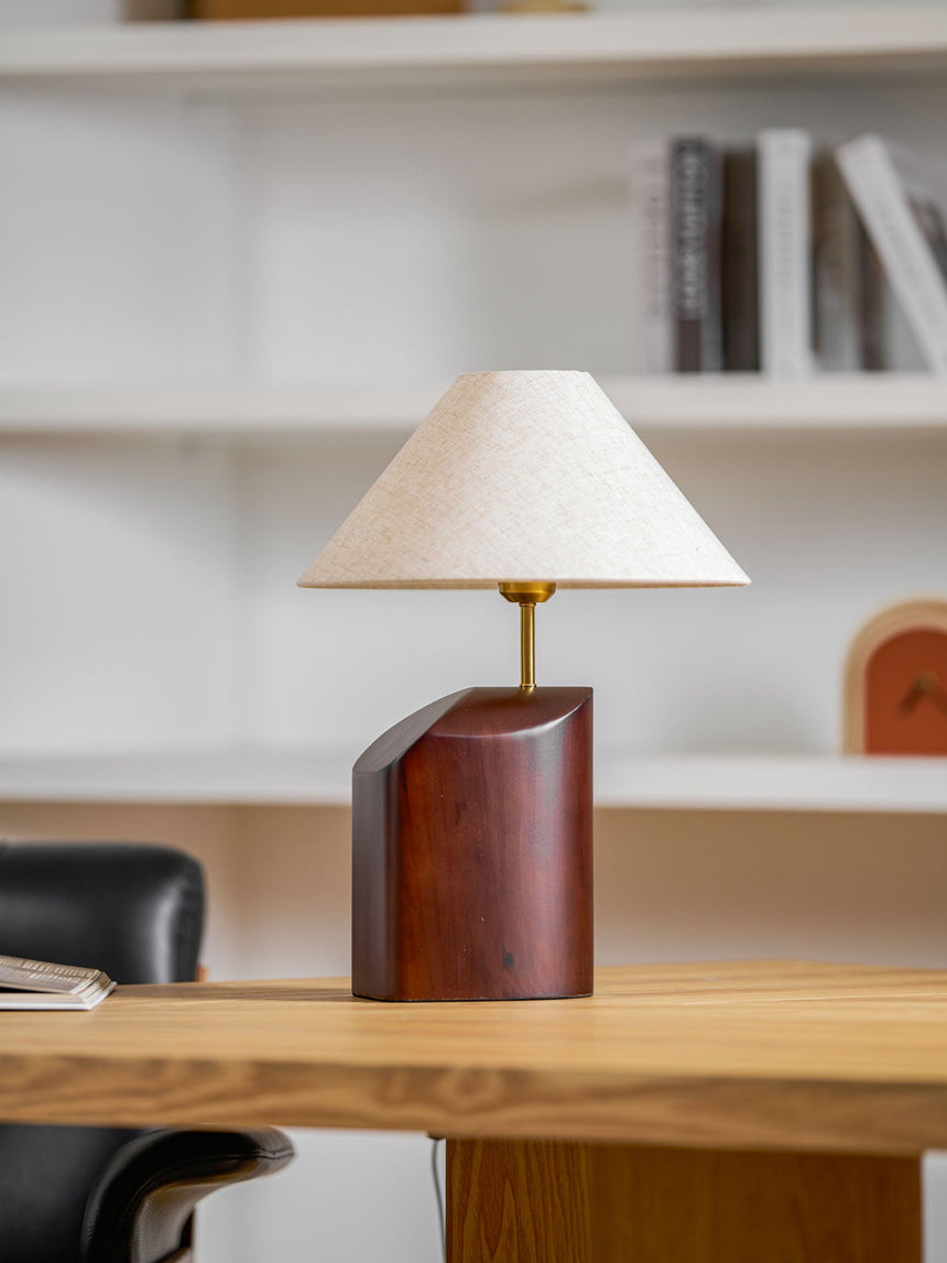 Bedroom table lamp lit on a desk beside an office chair