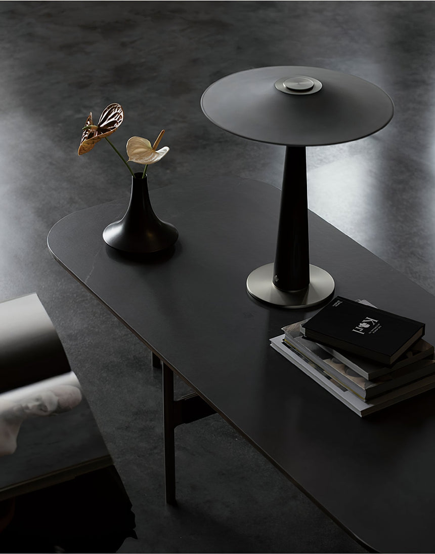 Bedroom table lamp unlit on a long dark bench beside books