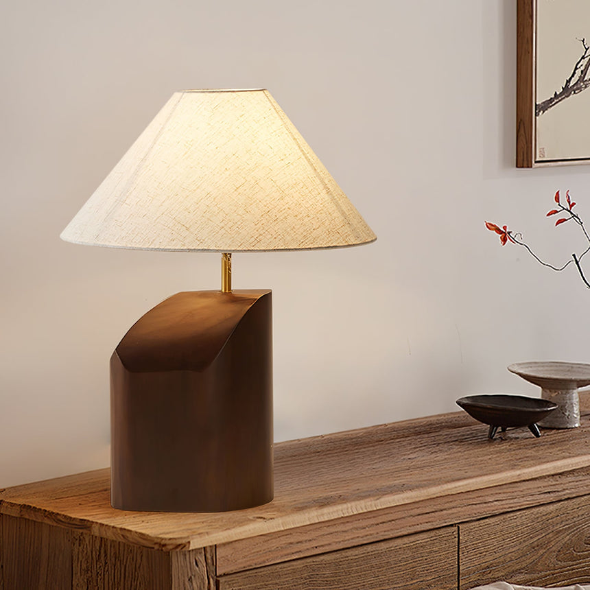 Bedroom table lamp lit on a sideboard beside a branch in a vase