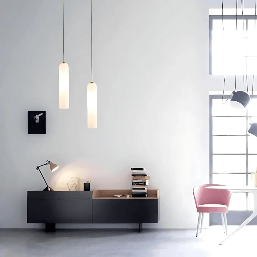 Two tube pendants lit above a desk with a chair and shelves