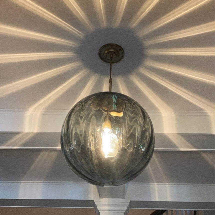 Smoke gray sphere lit under a ceiling patterned with fine rays of light