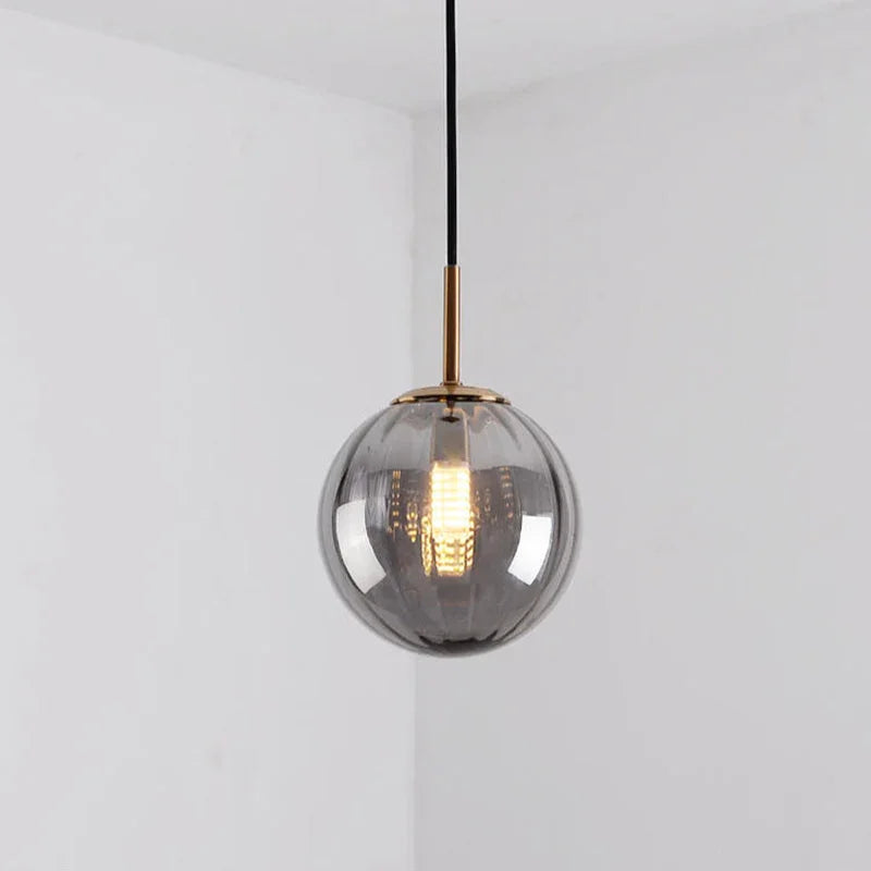 Smoke gray glass sphere with a brass holder and a lit bulb inside