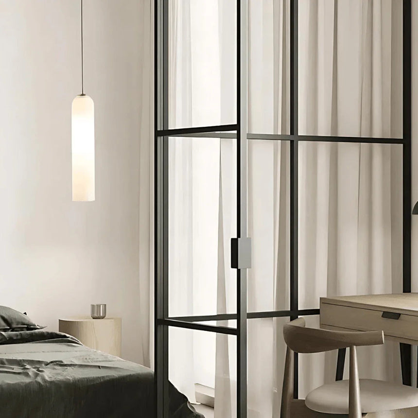 A white tube pendant lit in a corner beside a window frame